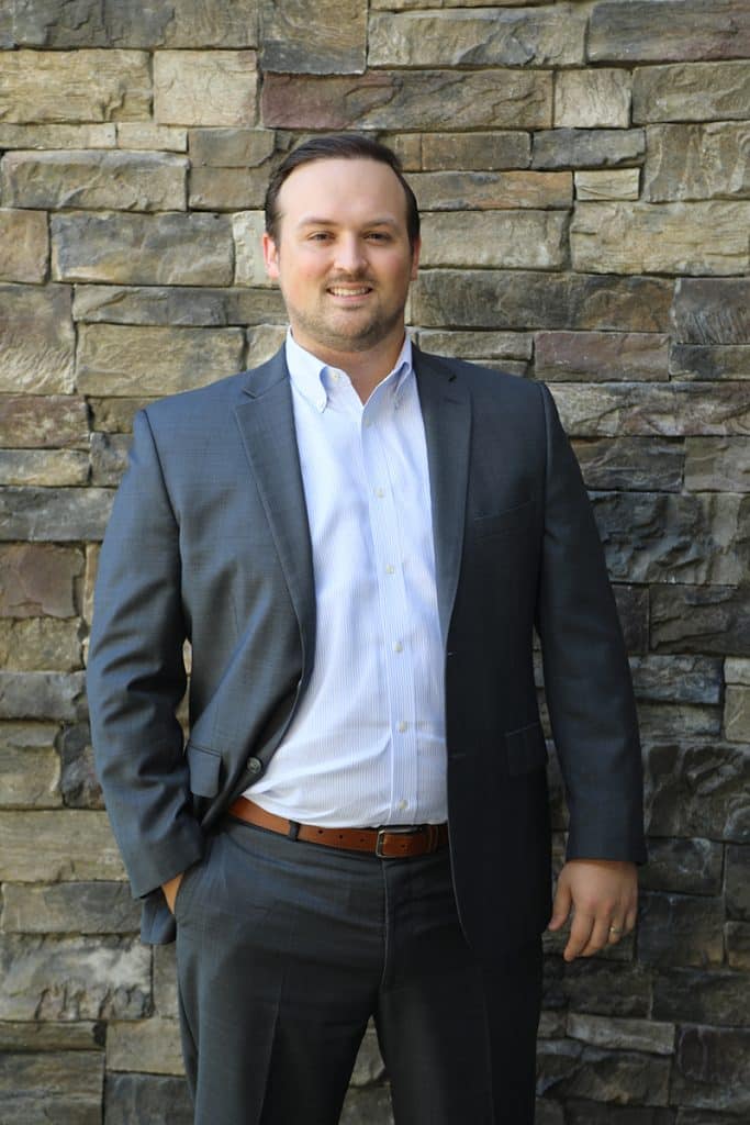 Man in business suit standing by stone wall